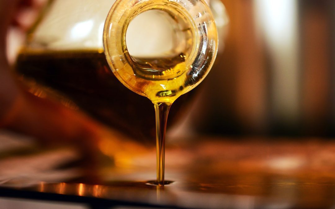 Aceite vegetal oliva virgen extra vertiéndose de una botella de cristal