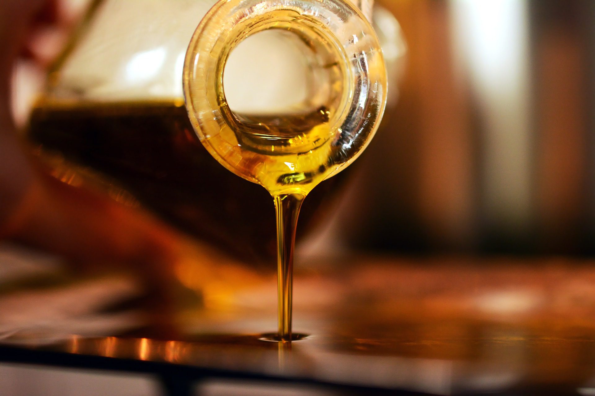 Aceite vegetal oliva virgen extra vertiéndose de una botella de cristal